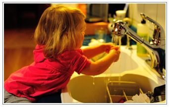 young girl washing hands in sink